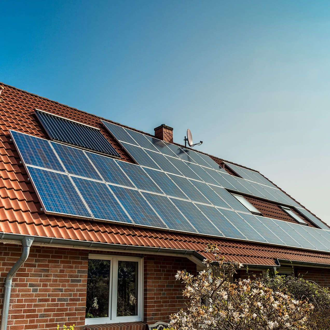 Einfamilienhaus mit Ziegeldach, ausgestattet mit Photovoltaik-Solarpaneelen. Der Einsatz erneuerbarer Energien zeigt Engagement für die Umwelt.